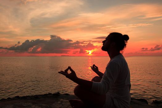 Yoga scene man silhouette in sunset background.