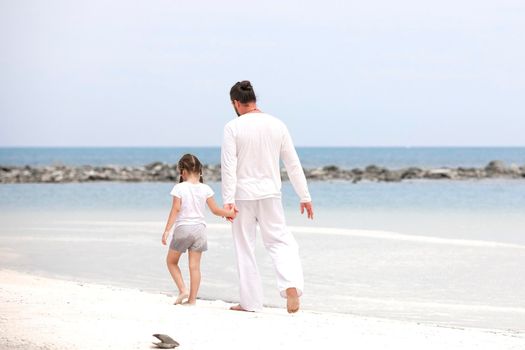 Adorable little girl holding her father hand. Healthy father and daughter playing together at the beach carefree happy fun smiling lifestyle