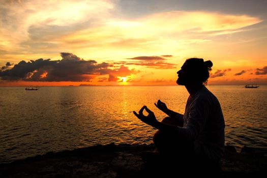 Yoga scene man silhouette in sunset background.