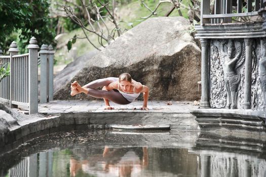 Young woman doing yoga in abandoned temple on wooden platform. Practicing in Thailand