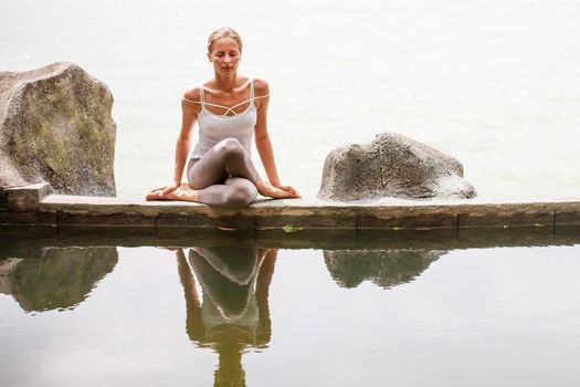 Woman practicing or doing morning meditation Yoga in nature at the beach