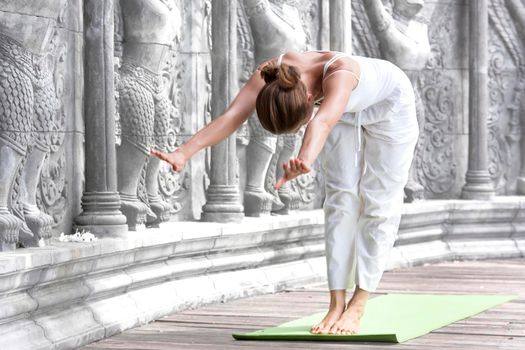 Beautiful strong Woman doing yoga pose in abandoned temple in Bali