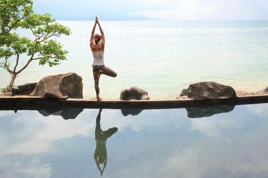 Woman practicing or doing morning meditation Yoga in nature at the beach