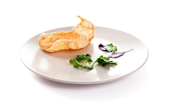 Molecular modern cuisine. Chips Pigskin on plate. Stock image. Isolated on white.