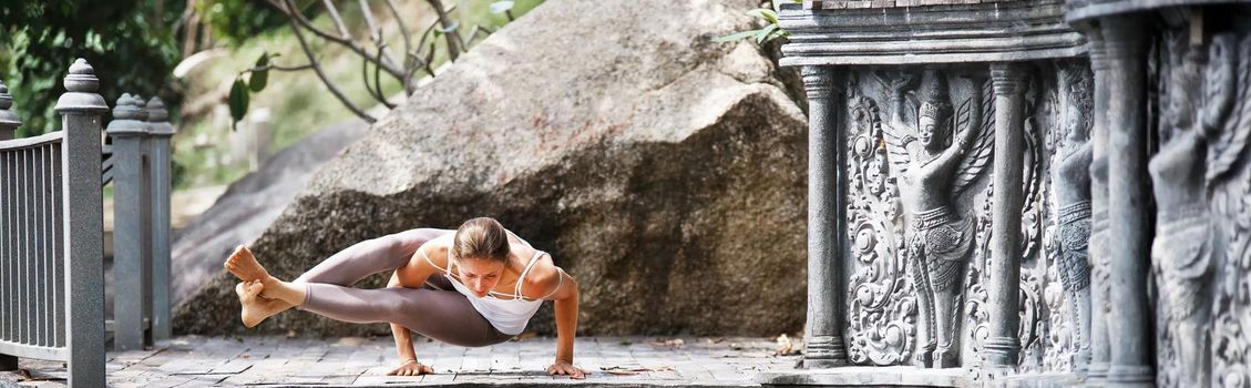 Young woman doing yoga in abandoned temple on wooden platform. Practicing in Thailand