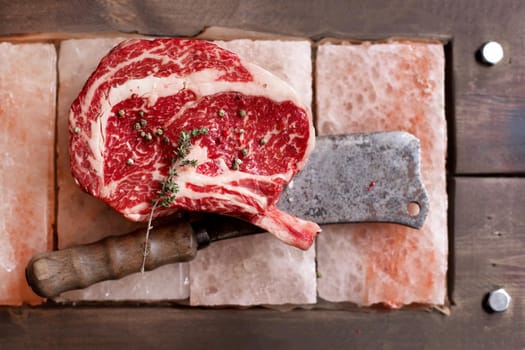 Bone In Rib Eye row Steak on pieces of salt on a wooden board. Stock image