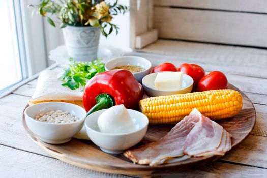 Ingredients for cooking Mexican Quesadilla wrap with vegetables, corn, sweet pepper and sauces on the parchment and table. horizontal view.