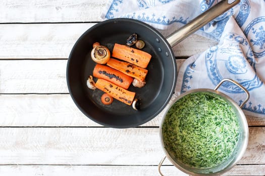 Ingredients for cooking Spinach soup with carrot and croutons in bowl on wooden table