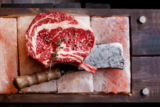 Bone In Rib Eye row Steak on pieces of salt on a wooden board. Stock image