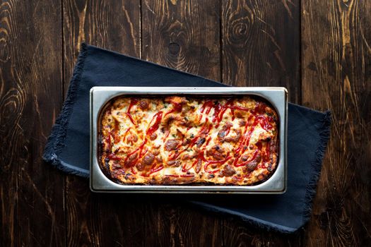 Italian Food. Hot tasty lasagna in ceramic casserole dish on Wooden Table