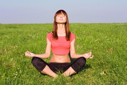 Woman sitting on the grass and doing yoga