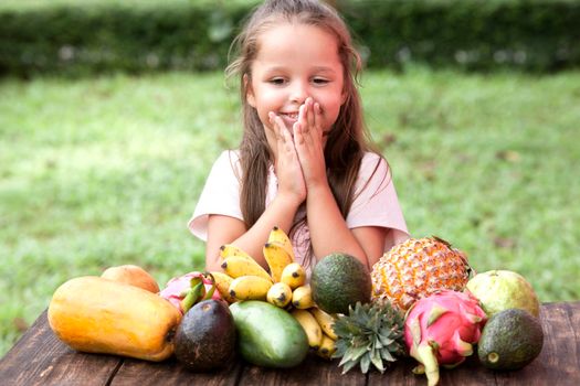 Exotic fruit on wooden table. Summer background with small Laughing happy girl