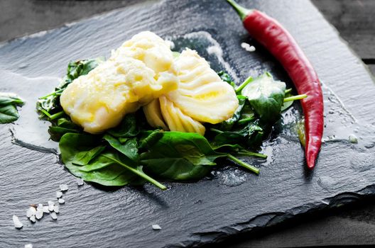 Delicious sea fish fillet with fresh healthy spinach and chili - Stock image