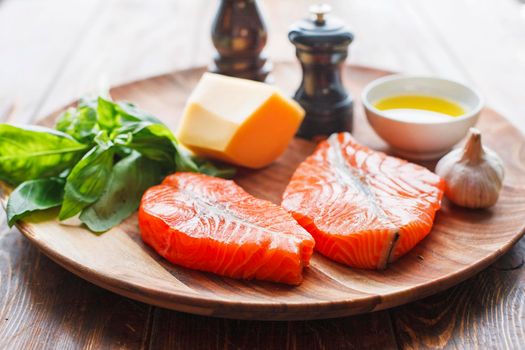 Raw humpback salmon steaks, cheese, rustic wooden background, above view. Fillet with fresh ingredients for tasty cooking and frying pan. Top view. Healthy and diet food concept.