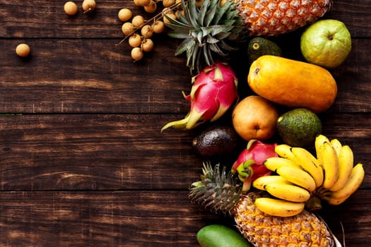 Fresh Tropical fruit on dark wooden background, top view