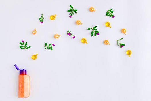 Bottle of essential oil with fresh meadow herbs and flowers on white background. Flat lay, top view, natural