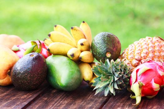 Fresh fruits. Mixed exotic fruits on wood background. Healthy eating, dieting. Top view with grass copy space