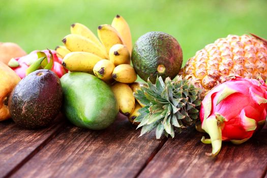 Fresh fruits. Mixed exotic fruits on wood background. Healthy eating, dieting. Top view with grass copy space