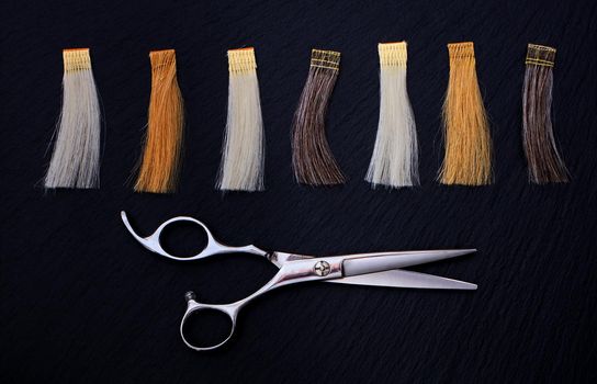 Hairdresser Accessories for coloring hair and Extensions colors on a black background. Scissors and hair samples