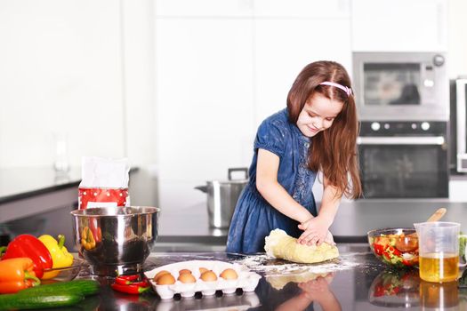 Sweet little cute girl is learning how to make a cake, in the home modern kitchen, Family concept