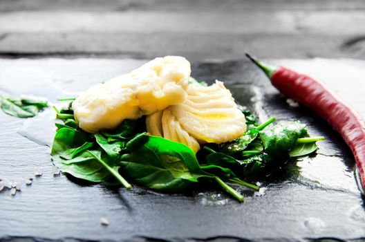 Delicious sea fish fillet with fresh healthy spinach and chili - Stock image