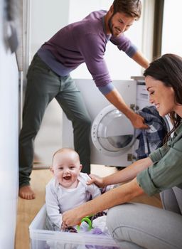 Shot of a young family having fun while doing laundry.
