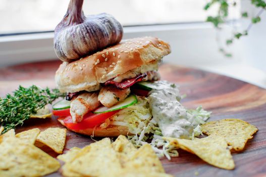 Creatively styled beef burger with rustic home-made French chips or crisps shot against light white background with generous accommodation for copy space. garlic on top