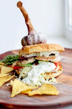 Creatively styled beef burger with rustic home-made French chips or crisps shot against light white background with generous accommodation for copy space. garlic on top