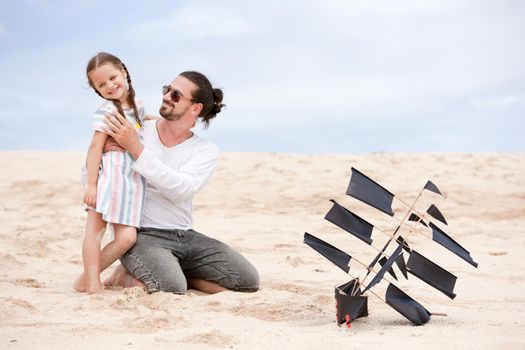 Beach cute girl with her happy father flying kite outdoor coast ocean