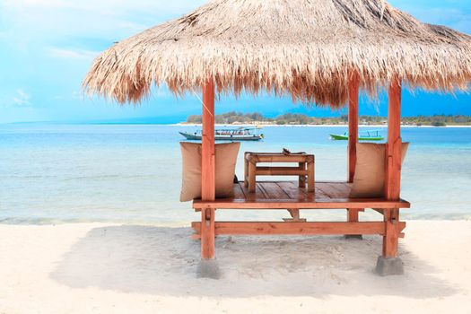 White wooden shelter with straw roof from the sun on the beach in Bali or Thailand. Gili island