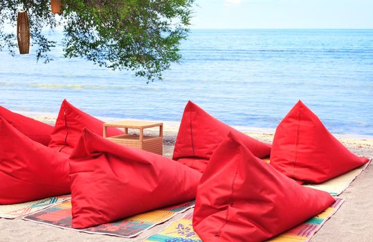 A lot of red Bean bags and table set on the ocean beach