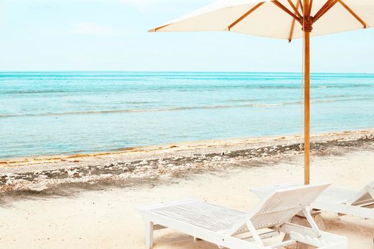 Beach Sun chairs and parasol on exotic tropical white sandy ocean beach