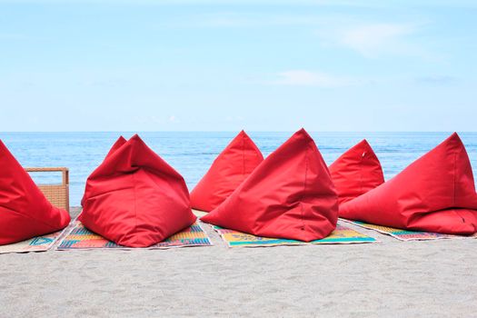 A lot of red Bean bags and table set on the ocean beach