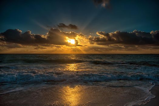 Sunset on the Caribbean Sea. The sun's rays make their way through the clouds.