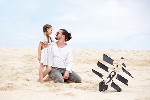 Beach cute girl with her happy father flying kite outdoor coast ocean