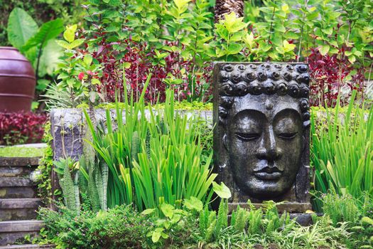 Buddha image with falling water in the tropical garden in Ubud, Bali, Indonesia