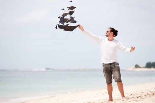 Happy man flying kite outdoor coast ocean. Beach vacation.