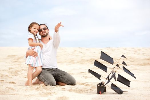 Beach cute girl with her happy father flying kite outdoor coast ocean