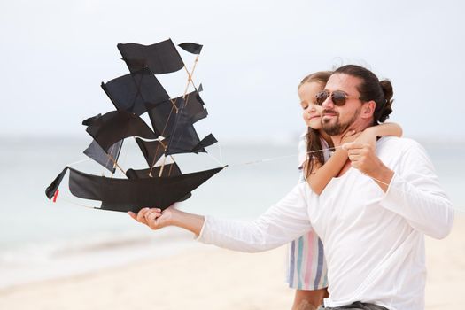 Beach cute girl with her happy father flying kite outdoor coast ocean