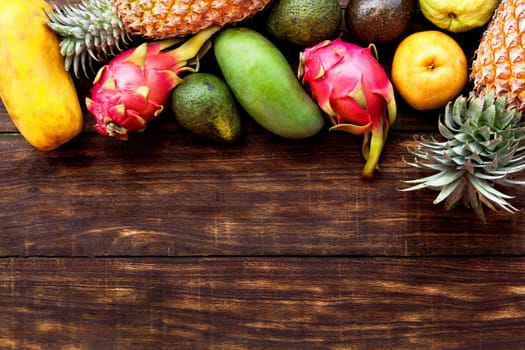 Fresh Tropical fruit on dark wooden background, top view