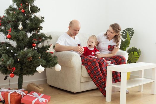 Baby child with hearing aid and cochlear implant having fun with parents in christmas room. Deaf and health