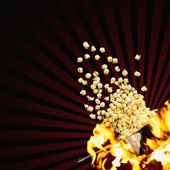Flying popcorn on a dark background. Hot popcorn flying from pot under fire. cinema popcorn design template. Advertising concept.