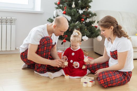 Baby child with hearing aid and cochlear implant having fun with parents in christmas room. Deaf and health