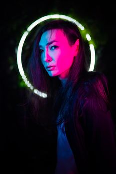 Portrait of an Asian man against the background of a circular lamp in the studio with neon light