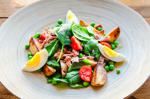 Tuna salad with lettuce, eggs and tomatoes on wooden plate