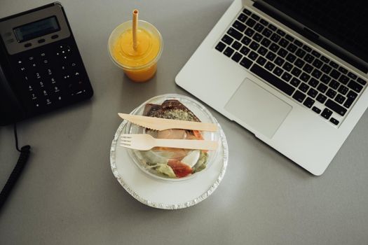 Flat Lay of Office Working Place, Lunch in the Boxes and Orange Drink on Table with Laptop and Telephone