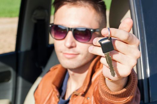 Man sitting inside car and showing keys to new car