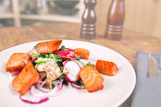 Red fish salmon with radish and spinach, served on white plate on wooden table. rustick style. View from above, top studio shot