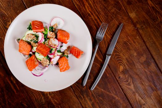 Broiled salmon with radish and spinach, served on white plate. View from above, top studio shot