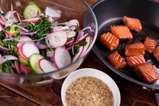 Ingredients. Broiled salmon with radish and spinach, served on wooden table. View from above, top studio shot